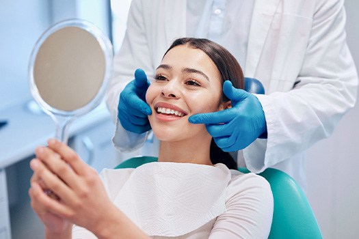 Woman smiling at reflection in handheld mirror