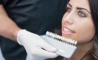 Dentist holding row of Lumineers to a patient's smile