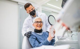 Senior woman in dental chair admiring her smile in mirror