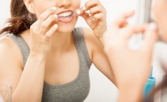 Woman placing take home teeth whitening tray in her mouth