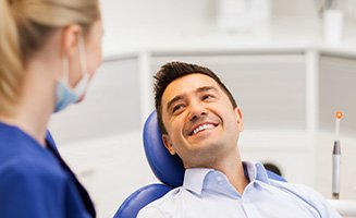 Patient in treatment chair smiling at dental assistant