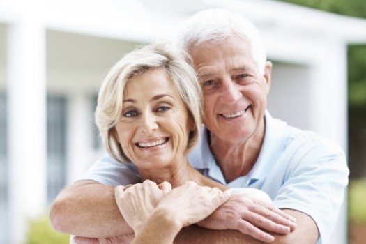 Senior man and woman hugging and smiling with dental implants in Edison
