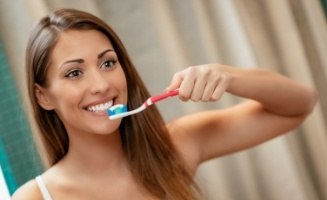 Woman smiling while brushing her teeth