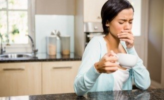Woman in her kitchen holding her cheek in pain