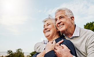 Senior couple smiling while hugging outside