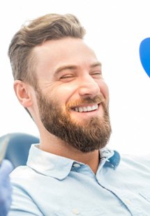 patient smiling while looking in dental mirror 