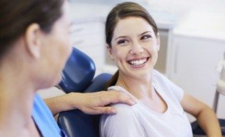 Dental team member placing their hand on shoulder of smiling dental patient