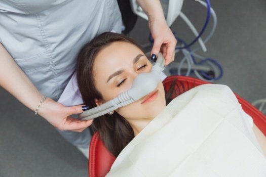 Woman in dental chair wearing mask for nitrous oxide sedation dentistry in Edison