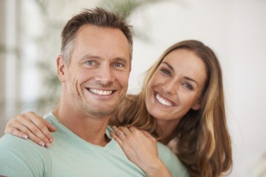 Smiling man and woman holding each other after teeth whitening in Edison