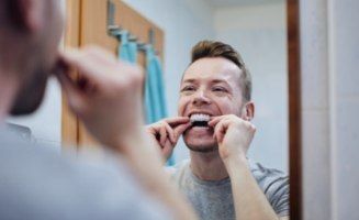 Man placing teeth whitening tray in his mouth
