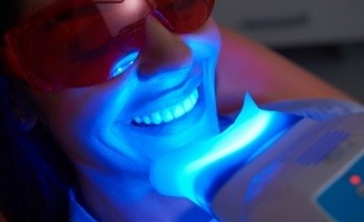 Woman getting U V teeth whitening from cosmetic dentist