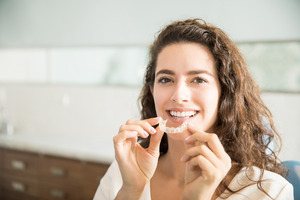 Woman sitting on couch about to put in clear aligner