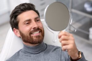 Man smiling into mirror after cosmetic dental treatment