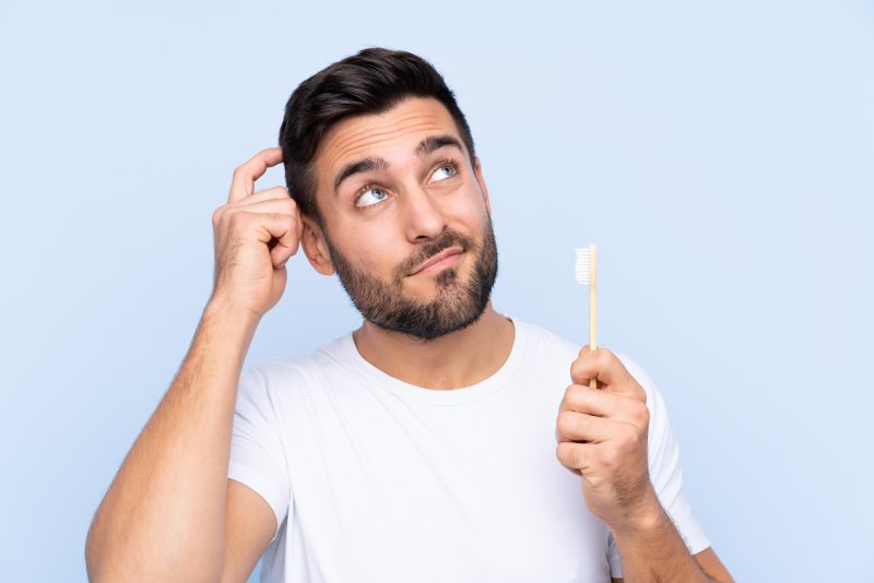 Patient scratching head and holding toothbrush