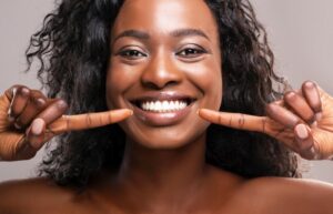 Woman with veneers pointing to her smile